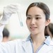 junge, chinesische Frau mit Reagenzglas in der Hand