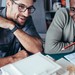 Zwei junge Männer sprechen über ein Architektur-Modell, das vor ihnen steht