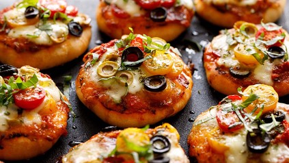 Pizza-Brötchen mit Oliven und Cocktailtomaten belegt.