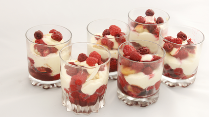 Sechs Gläschen gefüllt mit Himbeertiramisu vor weißem Hintergrund.