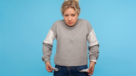 Junge Frau zeigt ihre leeren Hosentaschen und guckt hoffnungslos