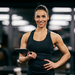 Junge sportliche Frau im Fitnessoutfit mit Tablet in der Hand.