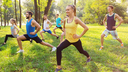 Eine Gruppe junger Menschen in Sportkleidung dehnt sich in Park.