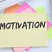 Ausschnitt von Arbeitsplatz mit Handy, Computermaus und Notizzettelblock, auf dem oben 'Motivation' steht.