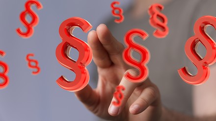 Mann zeigt auf Paragrafen-Symbole