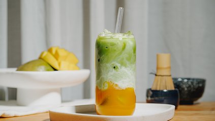 Mango Matcha Iced Latte im hohen Glas mit Glasstrohhalm.