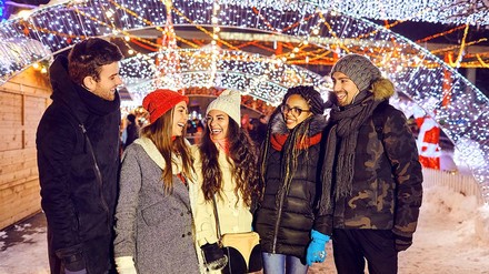 Studentengruppe in Winterkleidung abends einem Christkindlmarkt.