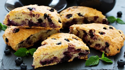 Blaubeer Scones aufgeschnitten, daneben liegt frische Minze und Blaubeeren