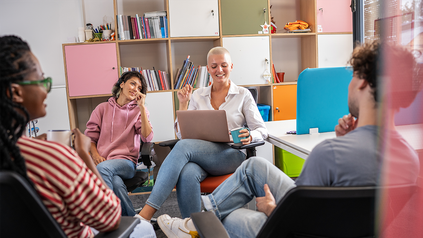 Vier junge Sozialarbeiter bei einem Gruppenmeeting in einem bunten Büroraum.