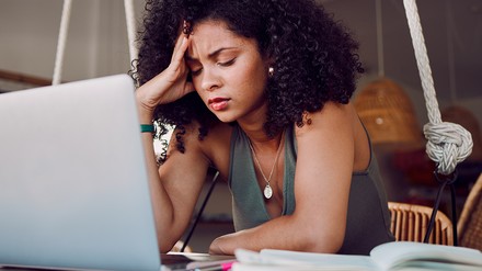 Studentin sitzt frustriert vor ihrem Laptop, daneben liegt ein Notizbuch