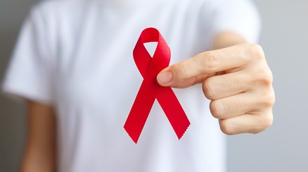 Junger Mann hält rote Schleife