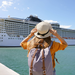Junge Frau mit Rucksack, die am Hafen vor einem Kreuzfahrtschiff steht.