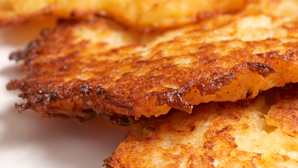 Nahaufnahme von drei übereinanderliegenden Kartoffelpuffern.