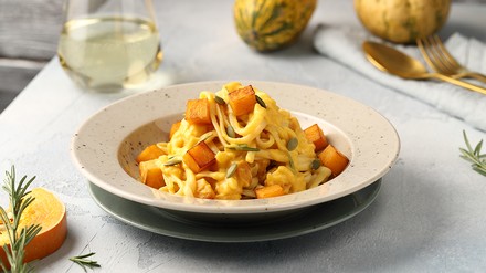 Kürbis-Linguine im Teller, im Hintergrund Kürbisse