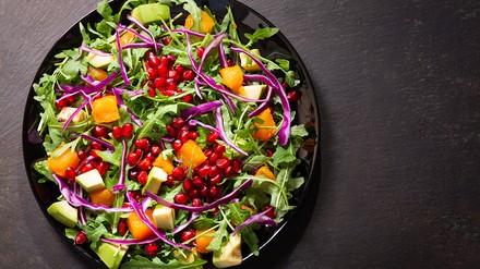 Top View von einer Salatschüssel mit Rucola, Granatapfelkernen, Avocado und Orangen