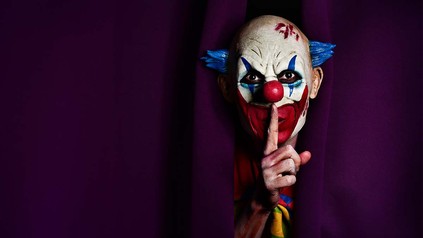 Gruselig aussehender Clown, mit Finger vor dem Mund.