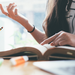 Ausschnitt von zwei jungen Frauen, die gemeinsam in der Bibliothek an einem Schreibtisch lernen.