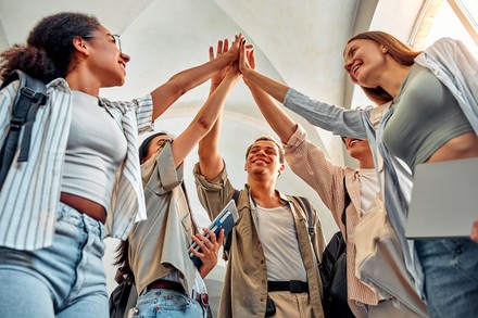 Eine Gruppe von Studienbeginnern geben sich High Five.