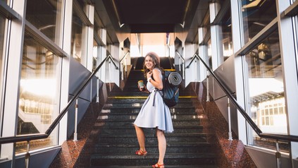 Frau mit Rucksack an einem Bahnhof bevor sie eine Reise antritt.