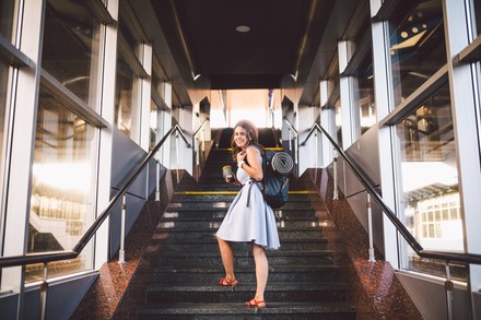 Frau mit Rucksack an einem Bahnhof bevor sie eine Reise antritt.