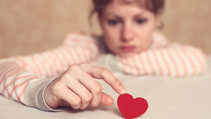 Frau verschwommen im Bild spielt mit kleinem roten Plastikherz.