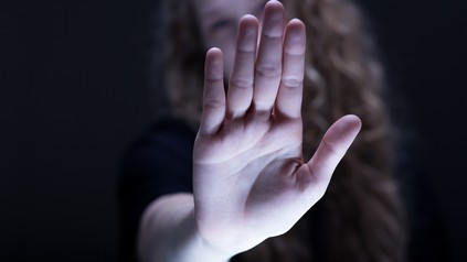 Frau streckt Hand abwehrend nach vorne.
