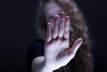 Frau streckt Hand abwehrend nach vorne.