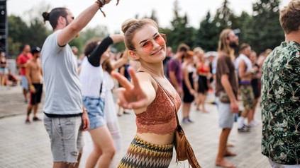 Eine Studentin feiert bei einem Open-Air-Festival vor einer Bühne.
