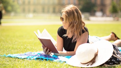 Studentin genießt einen schönen Sommertag und liest ein Buch.