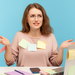 Junge Frau mit Brille sitzt ratlos am Schreibtisch vor ihrem Laptop, überall kleben bunte Post-it-Zettel.