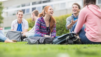 Junge Menschen sitzen auf dem Campus in der Wiese