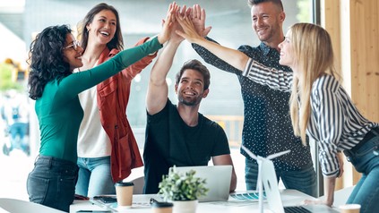 Junge Menschen am Arbeitsplatz geben sich ein High-Five