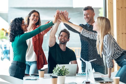 Junge Menschen am Arbeitsplatz geben sich ein High-Five