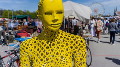 Flohmarkt in München, Theresienwiese, Frühlingsfest: Vielfalt bunt gemischt - verrückte gelbe Anziehpuppe, Kleiderpuppe, Schaufensterpuppe, Figur.
