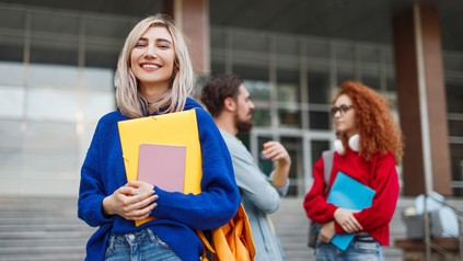 Drei junge Studenten schauen glücklich und lachend in die Kamera. Zwei Frauen und ein Mann.