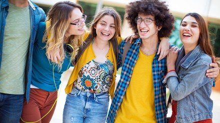 Vier junge Menschen lieben sich in den Armen und lachen.