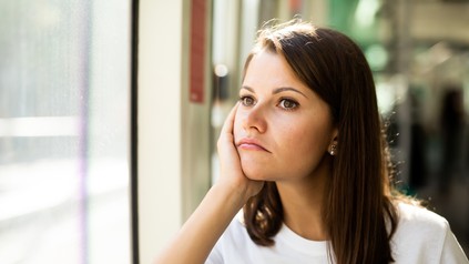 Studentin sitzt mit ernstem Gesicht am Fenster und grübelt.