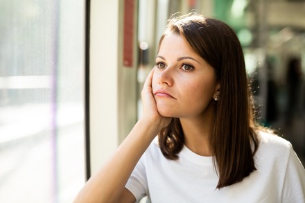 Studentin sitzt mit ernstem Gesicht am Fenster und grübelt.