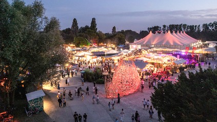 Luftaufnahme auf das abendliche, beleuchtete Festgelände.
