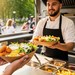 Foodtruck mit Kunden, zwei Portionen Pommes und einer Servicekraft