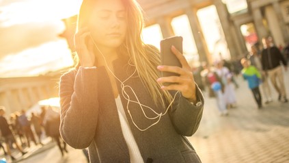 Junge Studentin vor dem Brandenburger Tor in der Abendsonne.