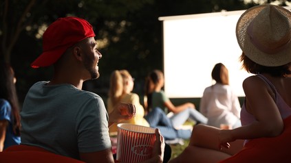 Studenten sehen sich im Open-Air-Kino einen Film an und essen Popcorn.