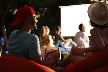 Studenten sehen sich im Open-Air-Kino einen Film an und essen Popcorn.