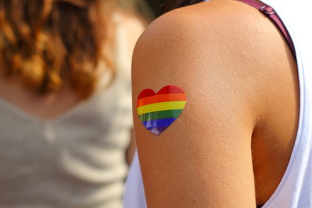 Eine junge Frau hat sich ein regenbogenfarbenes Herz auf den Arm geklebt.