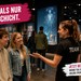 Junge Teammitarbeiterin spricht in einer modernen Ausstellung mit zwei Besucher:innen. Text im Bild wirbt für Studentenjobs bei Events.