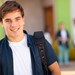 Abiturient steht erwartungsvoll mit seinen Unterlagen vor der Einschreibung an die Uni.