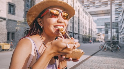 Eine Studentin lässt sich bei schönem Sommerwetter in der Kölner City einen Snack schmecken.