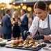 Lächelnde Köchin mit schwarzen Handschuhen, die bei einer Gartenparty im Freien Gourmet-Slider anrichtet.