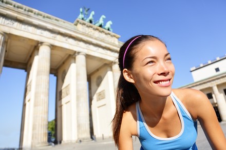 Junge Läuferin steht in sportlicher Haltung vor dem Brandenburger Tor beim Berlin-Marathon.