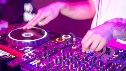 Nahaufnahme der Hände eines DJs, der in einem Nachtclub bei einer Party an einem Mixer Musik auflegt